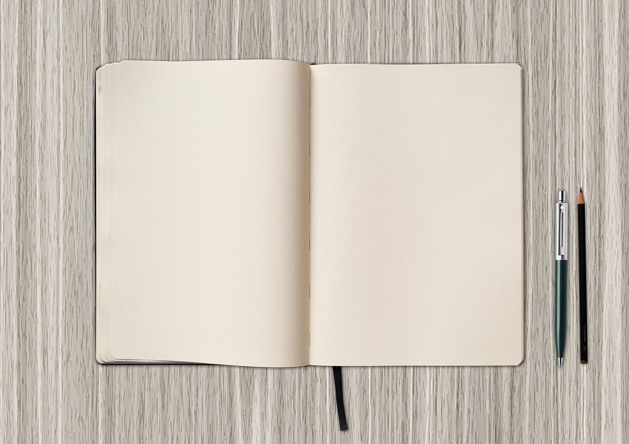 An open notebook and pens on a desk