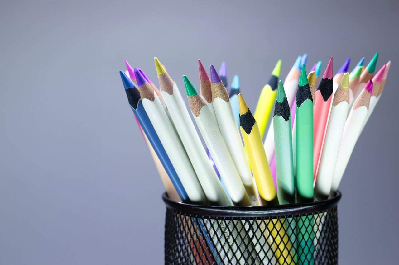 A pot of colourful pencils on a desk